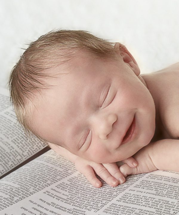 Newborn photography image in Huntsville, AL of a baby smiling on a bible