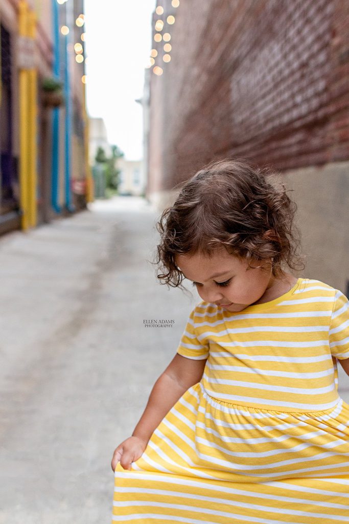 Picture of a little girl twirling her dress in downtown Huntsville, AL during her family pictures by Ellen Adams Photography.