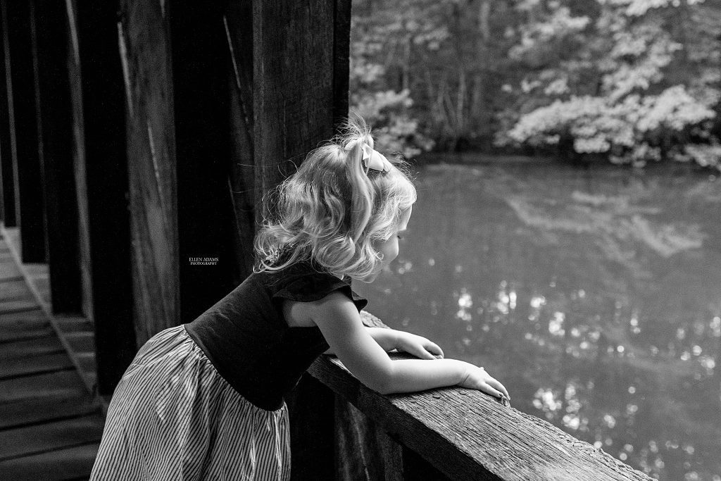 Little girl looking out of a window in a covered bridge.