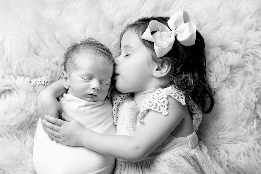 Newborn photographer in Huntsville, AL Ellen Adams Photography captured this image of a newborn kissed by his big sister