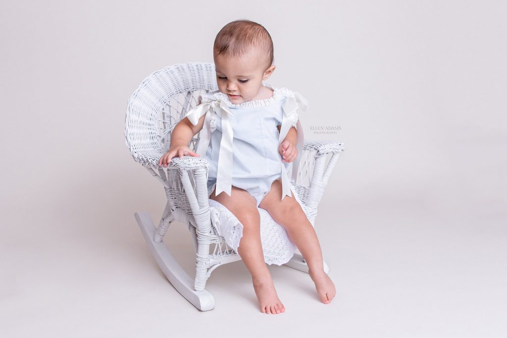 Baby photos of Madison AL with a baby sitting in a white wicker chair by Ellen Adams Photography.