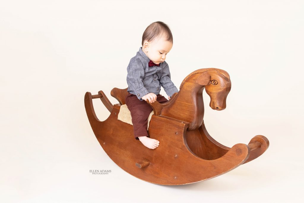 Baby riding a rocking horse by Ellen Adams Photography.